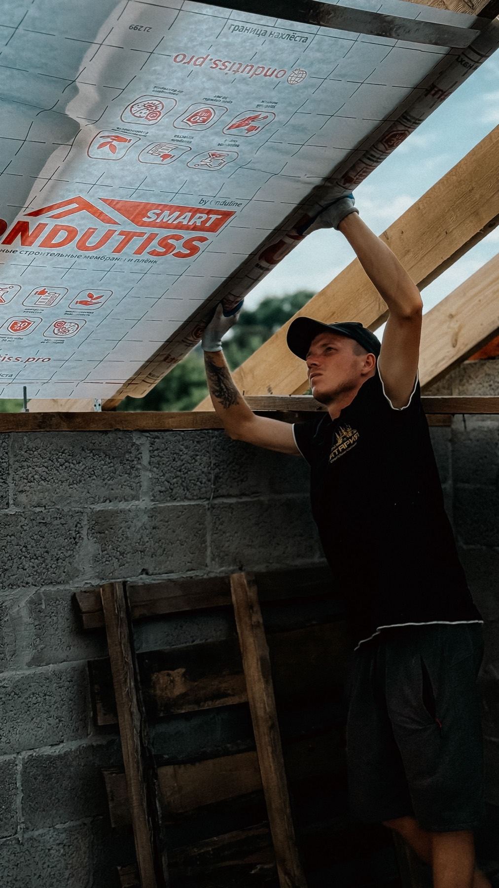 A worker installing insulation and a membrane to a roof on an unfinished building