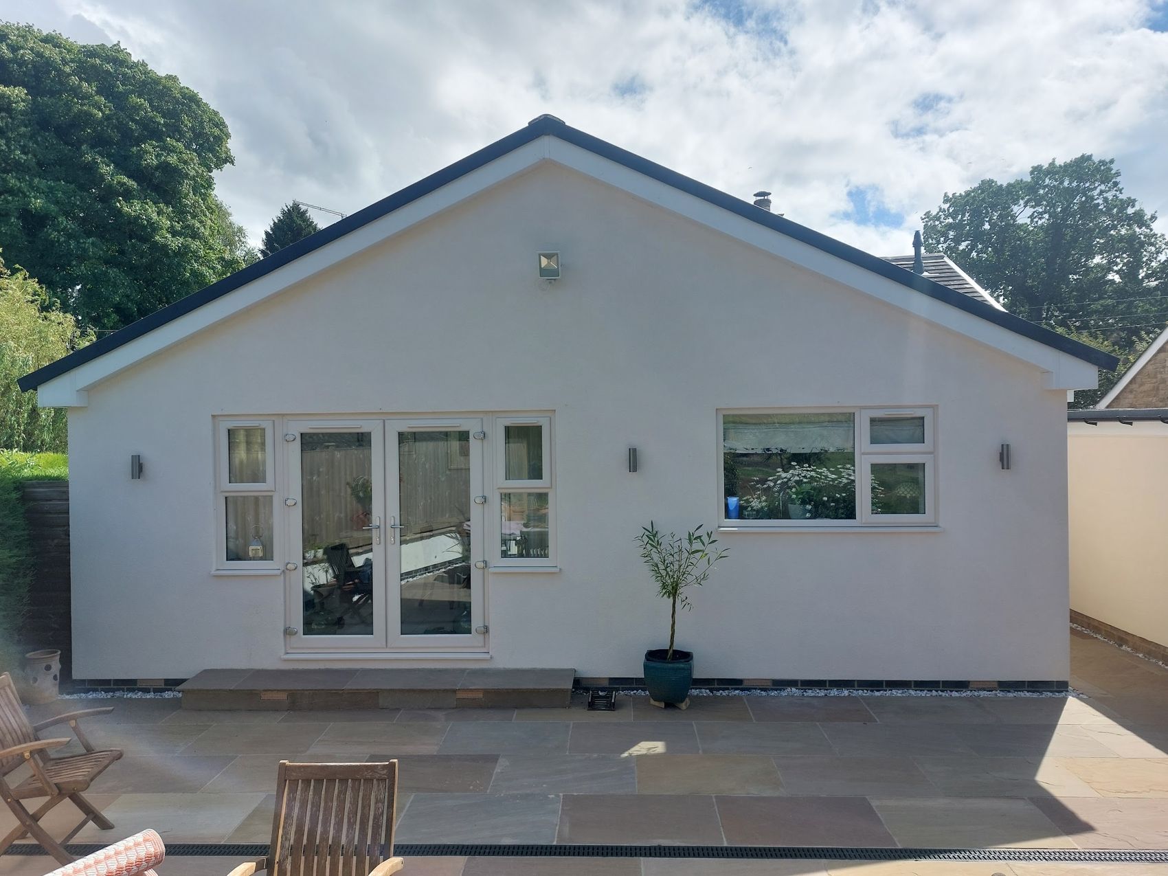 Rendered single-storey extension and stone terrace